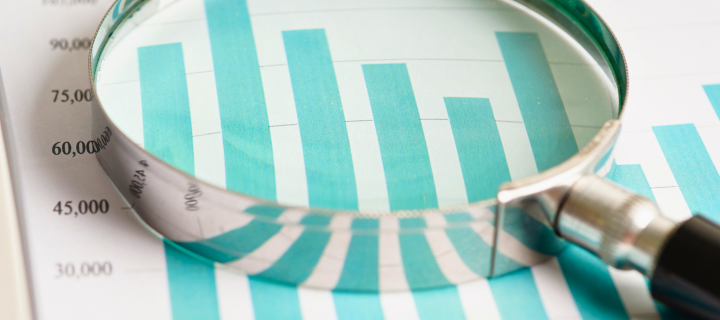 Magnifying glass examining teal financial bar chart, representing analysis of Autumn Budget 2025 changes